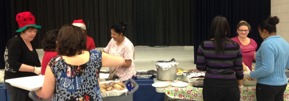 Parents wearing Christmas hats serving lunch to students