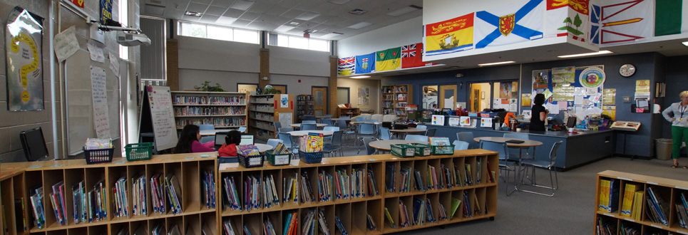 St. Teresa of Calcutta Catholic School library. Shelves of books, tables and chairs and posters and flags decorate the walls.