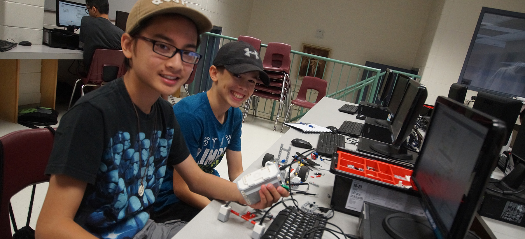 Two male students working on a computer and their robot